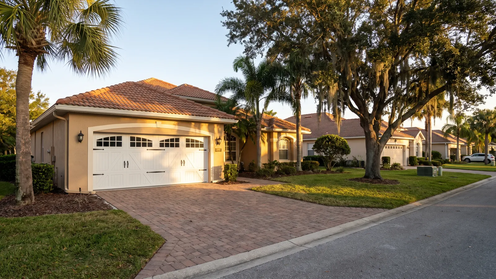 Newly installed white carriage-house style insulated steel garage door with arched windows on a tan stucco one-story home in Ocala, Florida